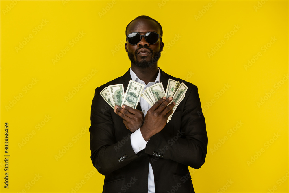 bearded luxury young afroamerican guy is holding lots of money in both